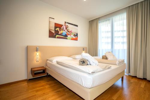 a bedroom with a large white bed in front of a window at Appartementhaus Karawankenhof in Villach