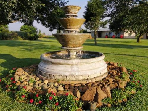 a fountain in the middle of a park with flowers at Forest Hill Country Lodge in Piet Retief
