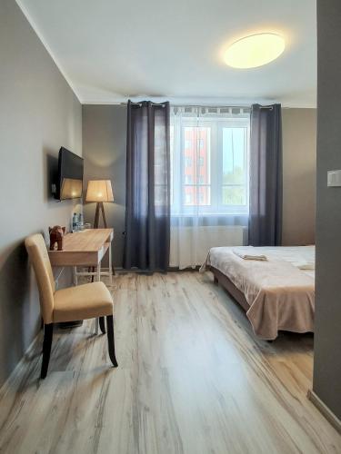a bedroom with a bed and a desk and a window at Kamienica Morska Gdynia in Gdynia