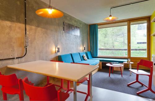 un salon avec une table et des chaises rouges dans l'établissement Les Lauzières, à Arc 1800