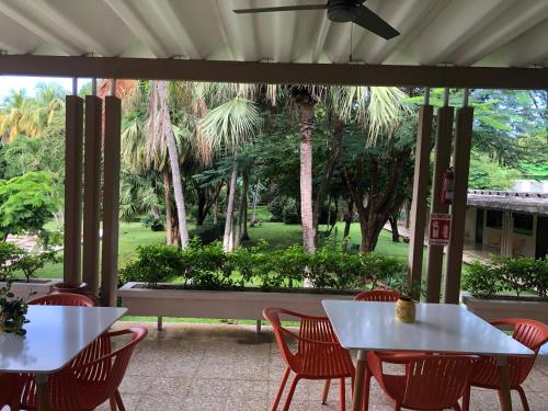 a patio with white tables and chairs and palm trees at Hotel Diriá Santa Cruz in Santa Cruz