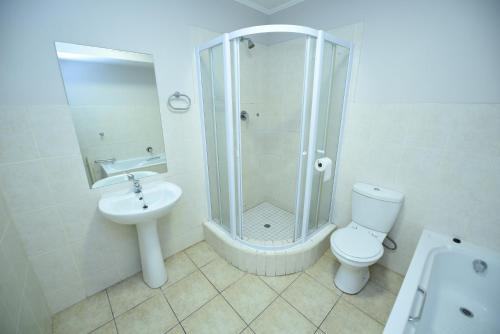 a bathroom with a shower and a toilet and a sink at The Island Club Apartment in Cape Town