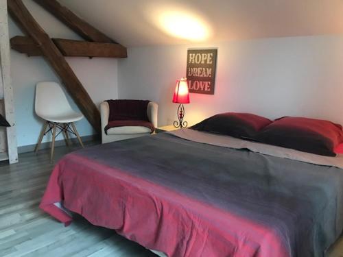a bedroom with a large bed and a chair at la menuiserie in Jeuxey