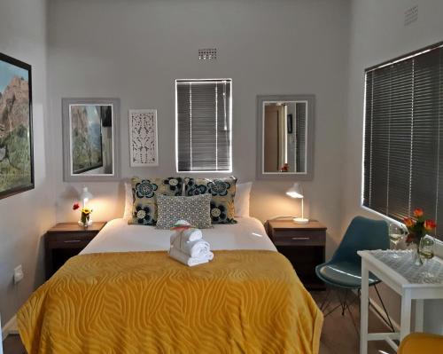 a bedroom with a bed with a yellow bedspread at 16 Rhodes-North Self Catering Apartment & Studio in Stellenbosch