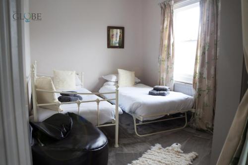 a bedroom with two beds and a window at The Globe Angle in Pembrokeshire