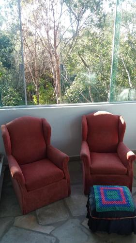 two red chairs sitting in a room with a window at Morada dos Elfos in Vale do Capao