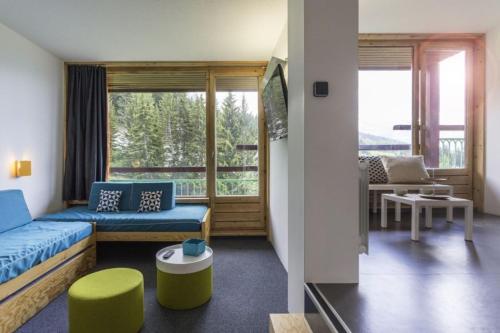 un salon avec un canapé bleu et un balcon dans l'établissement Les Lauzières, à Arc 1800