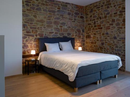 een bed in een kamer met een bakstenen muur bij Le Merle - Bois-de-Villers in Profondeville