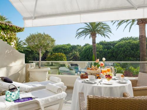 a patio with white furniture and a view of the ocean at Hôtel Juana in Juan-les-Pins