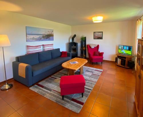 ein Wohnzimmer mit einem blauen Sofa und roten Stühlen in der Unterkunft Ferienwohnungen Dargatz in Lüßvitz