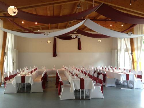 a banquet hall with white tables and red chairs at Hotel Haus am Ahorn in Schöneck