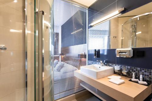 a bathroom with a shower, sink, and mirror at Tempus Club Garni Hotel in Bratislava