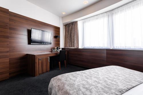 a hotel room with a bed and a desk with a television at Tempus Club Garni Hotel in Bratislava