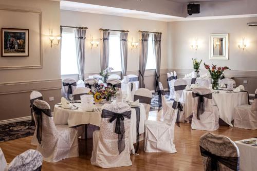 pokój pełen stołów i krzeseł z białymi tkaninami w obiekcie Gullane's Hotel w mieście Ballinasloe