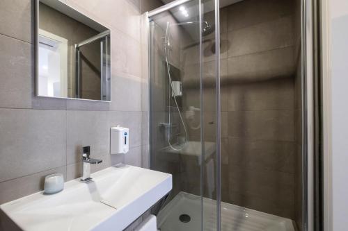 y baño con lavabo y ducha acristalada. en Magma Hostel en Ponta Delgada
