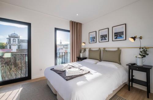 a bedroom with a white bed and a large window at Magma Hostel in Ponta Delgada