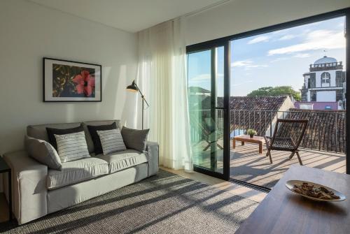 a living room with a couch and a sliding glass door at Magma Hostel in Ponta Delgada