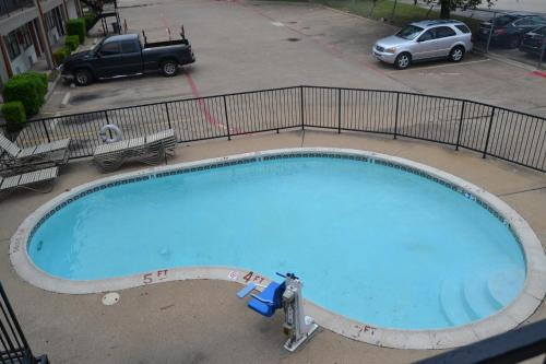 a large blue swimming pool in a parking lot at Deluxe Inn Irving in Irving