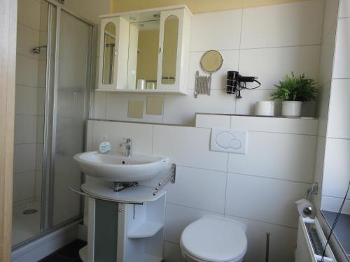 a white bathroom with a sink and a toilet at Haus Sandra Ferienwohnung 2 in Dahme