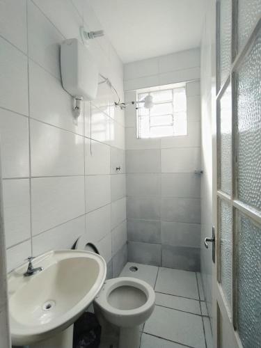 a white bathroom with a sink and a toilet at Palace Hotel in Curitiba
