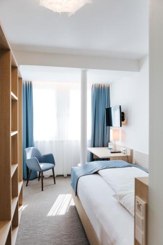 a hotel room with a bed and a chair at Sankt Magdalena in Linz