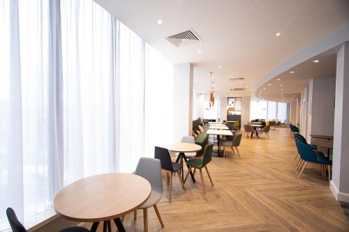 a cafeteria with tables and chairs and large windows at Holiday Inn Preston by IHG in Preston