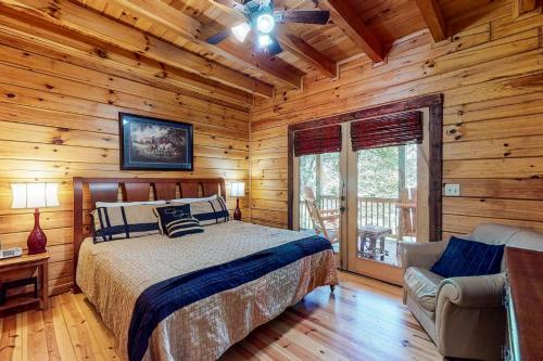 ein Schlafzimmer mit einem Bett und einem Stuhl in einer Blockhütte in der Unterkunft Mi casa es su Casa in Blue Ridge