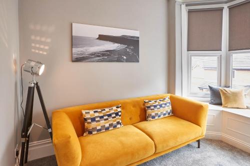 un sofá amarillo en una sala de estar con ventana en Host & Stay - Fly Away at Ruby, en Saltburn-by-the-Sea