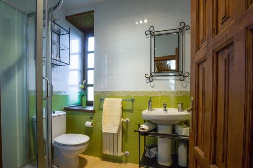 a bathroom with a white toilet and a sink at El Balcón De Muniellos in Oballo