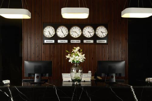 a room with clocks on the wall and a table with flowers at Tripper Inn Hotel in Dammam