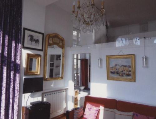 a living room with a couch and a mirror at Au Soleil Couchant in Trouville-sur-Mer