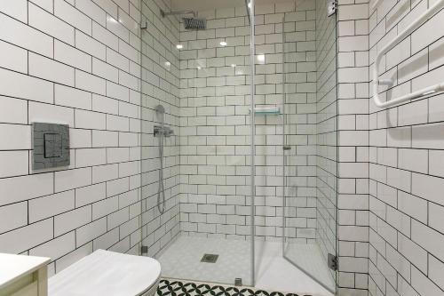 ein weiß gefliestes Bad mit einer Dusche und einem WC in der Unterkunft LovelyStay - 2BR Flat with AC in Duque de Loulé in Porto