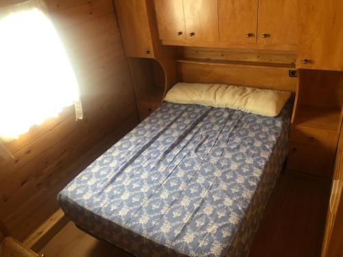 a bed in a wooden cabin with a window at Bungalós Las Nieves in Puebla de Lillo