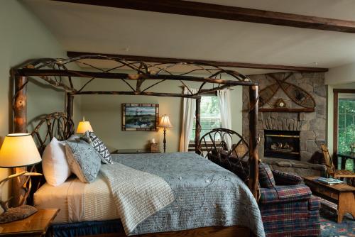 a bedroom with a wooden canopy bed and a fireplace at Strong House Inn in Vergennes