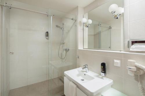 a white bathroom with a sink and a shower at Hotel Kultúra in Ružomberok