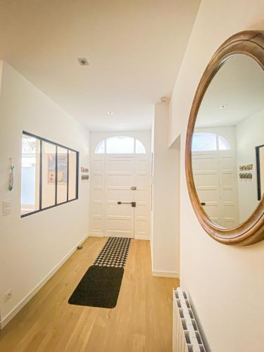 a hallway with a round mirror and a door at APT bord de Mer, hypercentre Dinard, Parking prive in Dinard