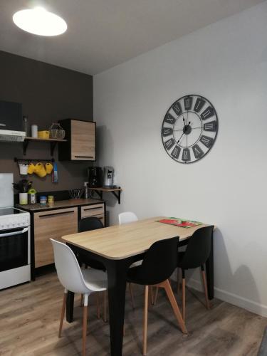 une cuisine avec une table et une horloge au mur dans l'établissement Joli appt cocooning au pied des dunes, à Berck-sur-Mer