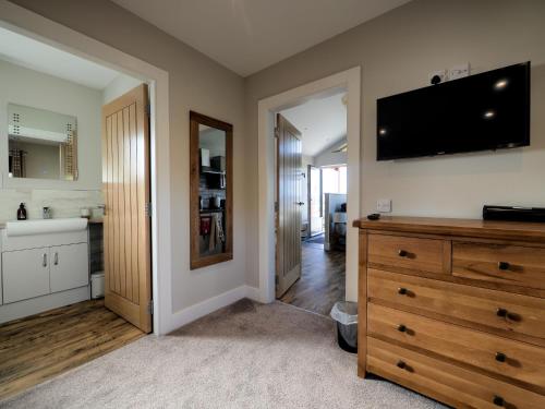 a kitchen with a dresser and a tv on the wall at Craigard Chalet in Portree