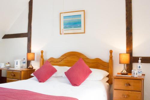 a bedroom with a bed with two red pillows at Moss Cottage in Stratford-upon-Avon