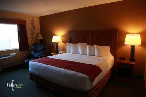 una habitación de hotel con una cama grande y una silla en AmericInn by Wyndham McAlester, en McAlester