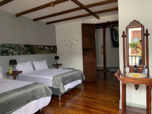 a bedroom with two beds and a mirror at La Estancia Hotel Boutique in Salamina