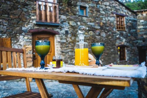 CandalMontanhas do Xisto - Casa da Parreira的一张桌子,上面放着两杯和一瓶橙汁