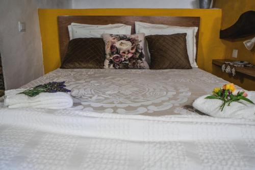 a white bed with two pillows and flowers on it at Montanhas do Xisto - Casa da Parreira in Candal