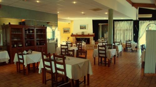 a restaurant with tables and chairs and a fireplace at Cit'Hôtel- Hôtel d'Occitanie in Pont-du-Casse