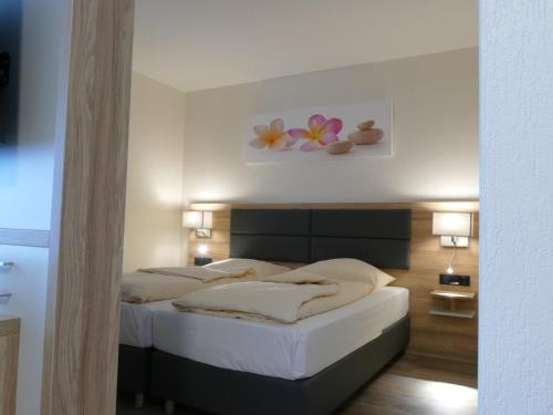 ノイ・ヴルムシュトルフにあるLandhaus Mienenbüttelのベッドルーム1室(白いシーツと花の壁付)