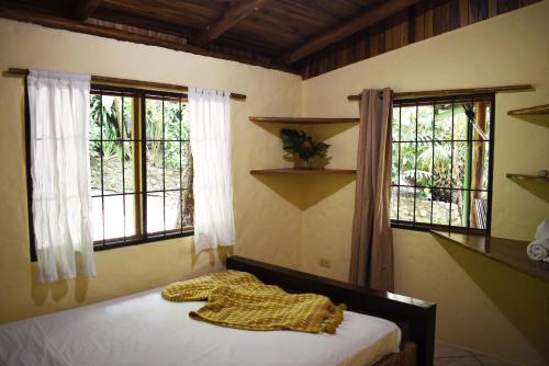 a bedroom with a bed and two windows at Pachamama Tropical Garden Lodge in Carmen