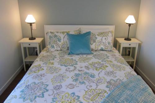 een bed met een blauw kussen en twee nachtkastjes bij Lotus Loft in Victoria