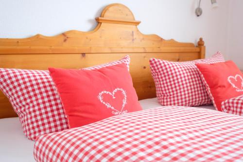 a bed with red and white pillows on it at Alpenflora Ferienwohnungen in Ofterschwang