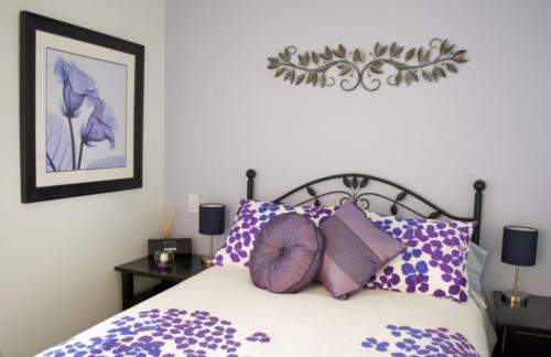 a bedroom with a purple and white bed with purple pillows at Urban Den in Victoria