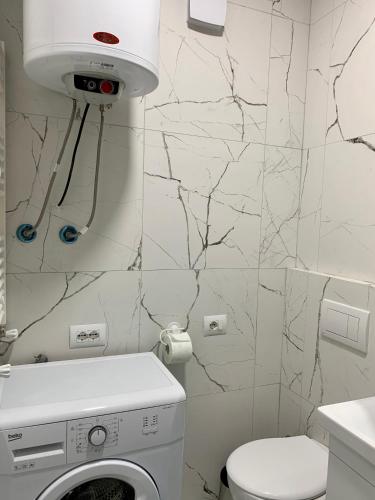 a bathroom with a toilet and a washing machine at Blini Studio Apartment in Pristina